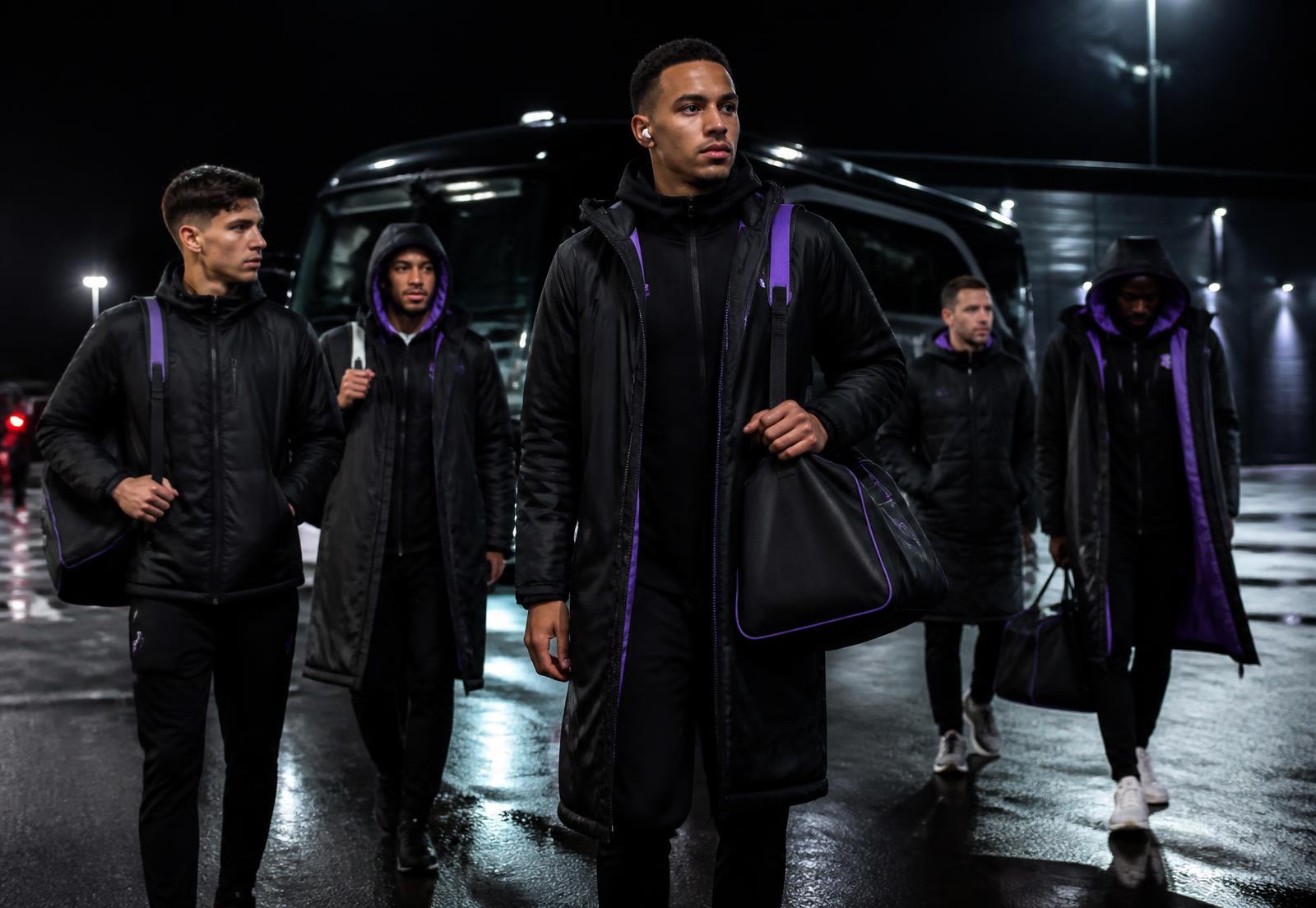 A squad arriving at a stadium at night in Hackin outerwear carrying Hackin bags